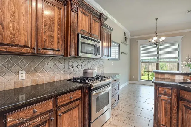a kitchen with stainless steel appliances granite countertop a sink a stove and cabinets
