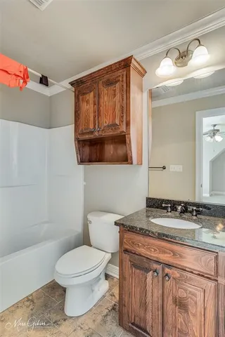 a bathroom with a granite countertop toilet sink and mirror