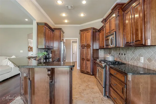 a kitchen with stainless steel appliances granite countertop a sink a stove and a refrigerator