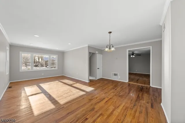 a view of an empty room with window and wooden floor