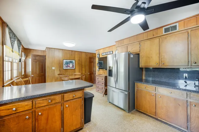 a view of a hallway with wooden floor windows a fireplace and kitchen view