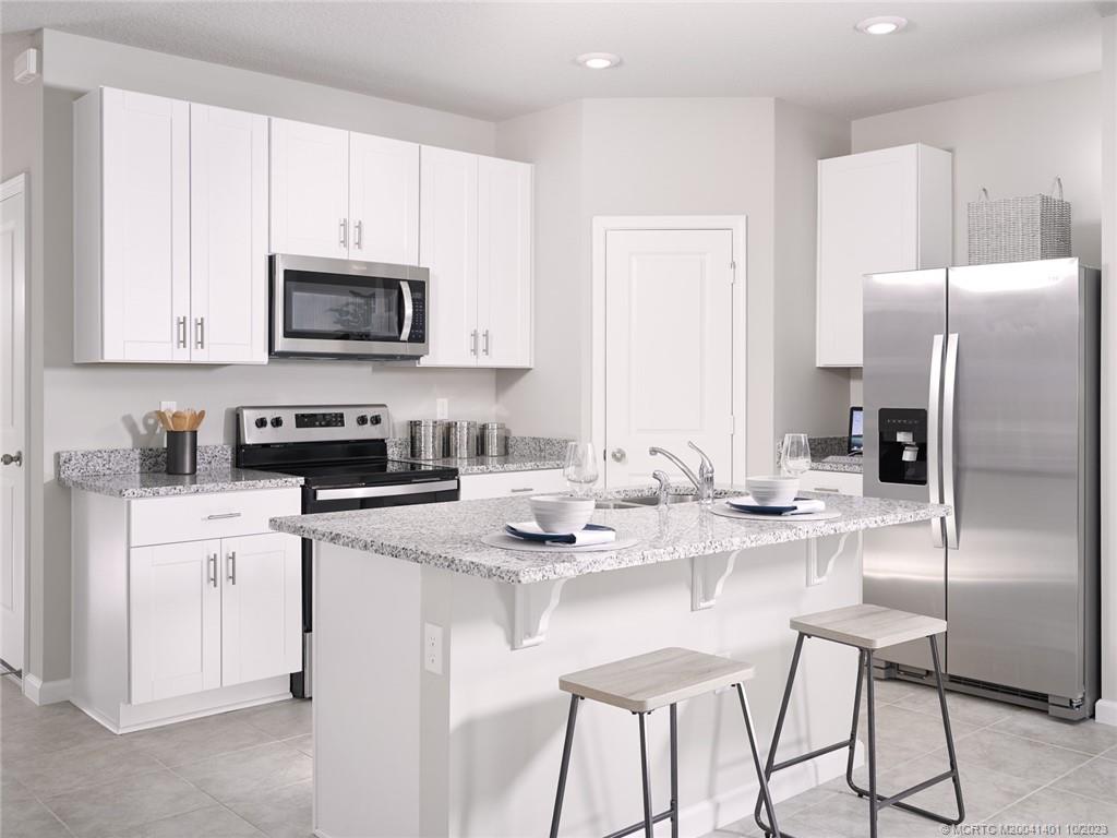 5718 Southeast Edgewater Circle Stuart, FL 34997 - Photo 3 of 9 a kitchen with stainless steel appliances granite countertop a refrigerator a stove a sink a dining table and chairs