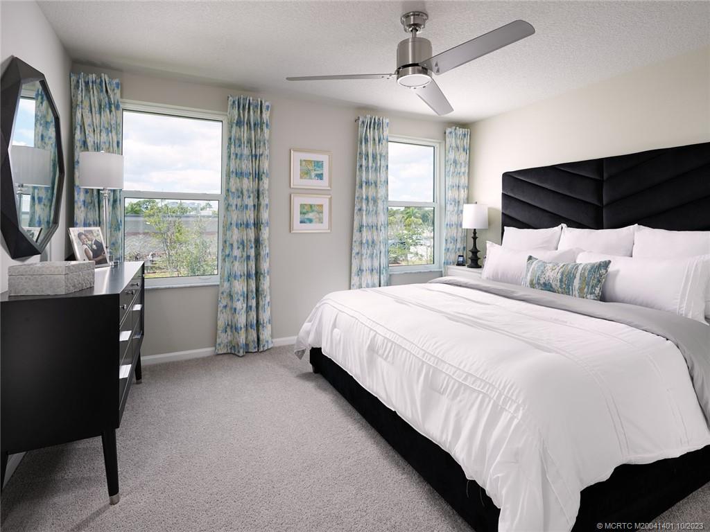 5718 Southeast Edgewater Circle Stuart, FL 34997 - Photo 8 of 9 a bedroom with a bed a mirror and a large window