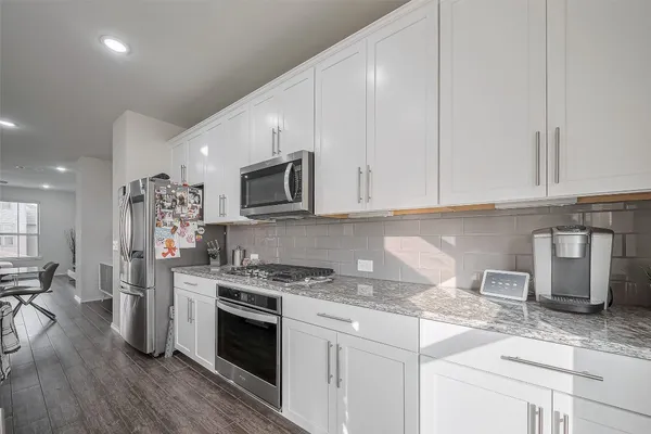 a kitchen with granite countertop a sink cabinets and stainless steel appliances