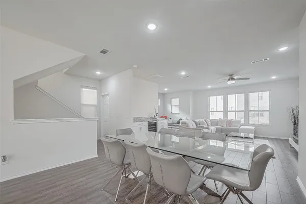 a kitchen with a dining table chairs wooden floor appliances and cabinets