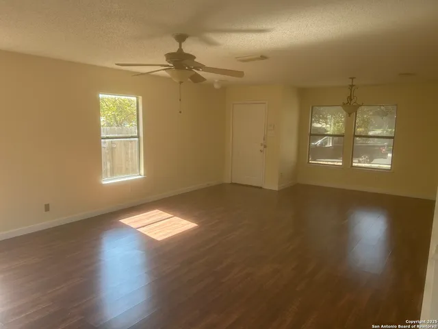 a view of empty room with wooden floor and fan