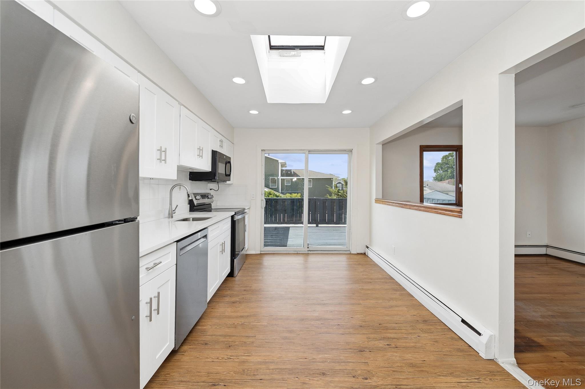 2625 Riverside Drive Wantagh, NY 11793 - Photo 10 of 20 a large white kitchen with granite countertop a refrigerator a sink a stove and white cabinets with wooden floor