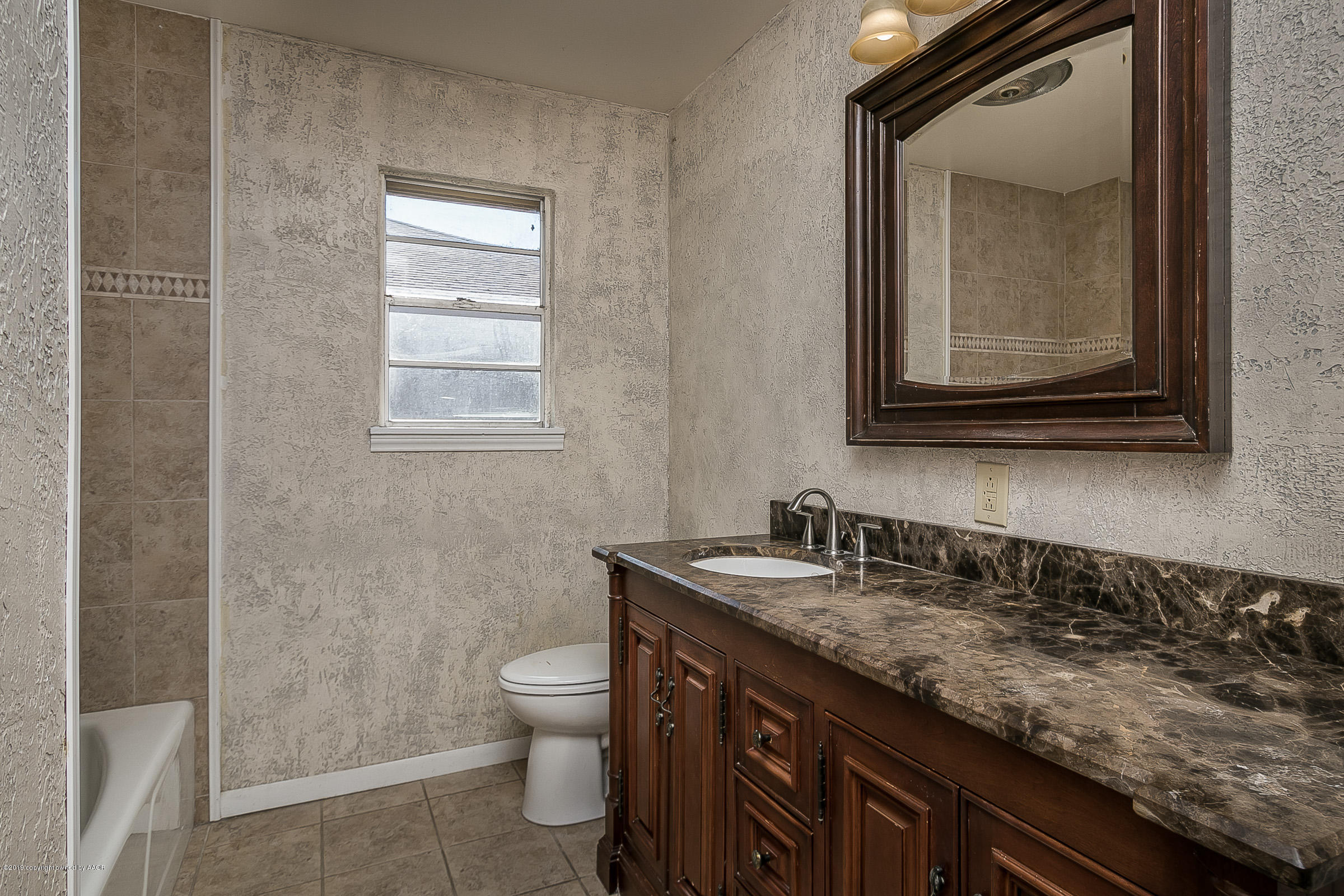 6016 Elmhurst Road Amarillo, TX 79106 - Photo 16 of 21 a bathroom with a granite countertop sink a toilet and a mirror