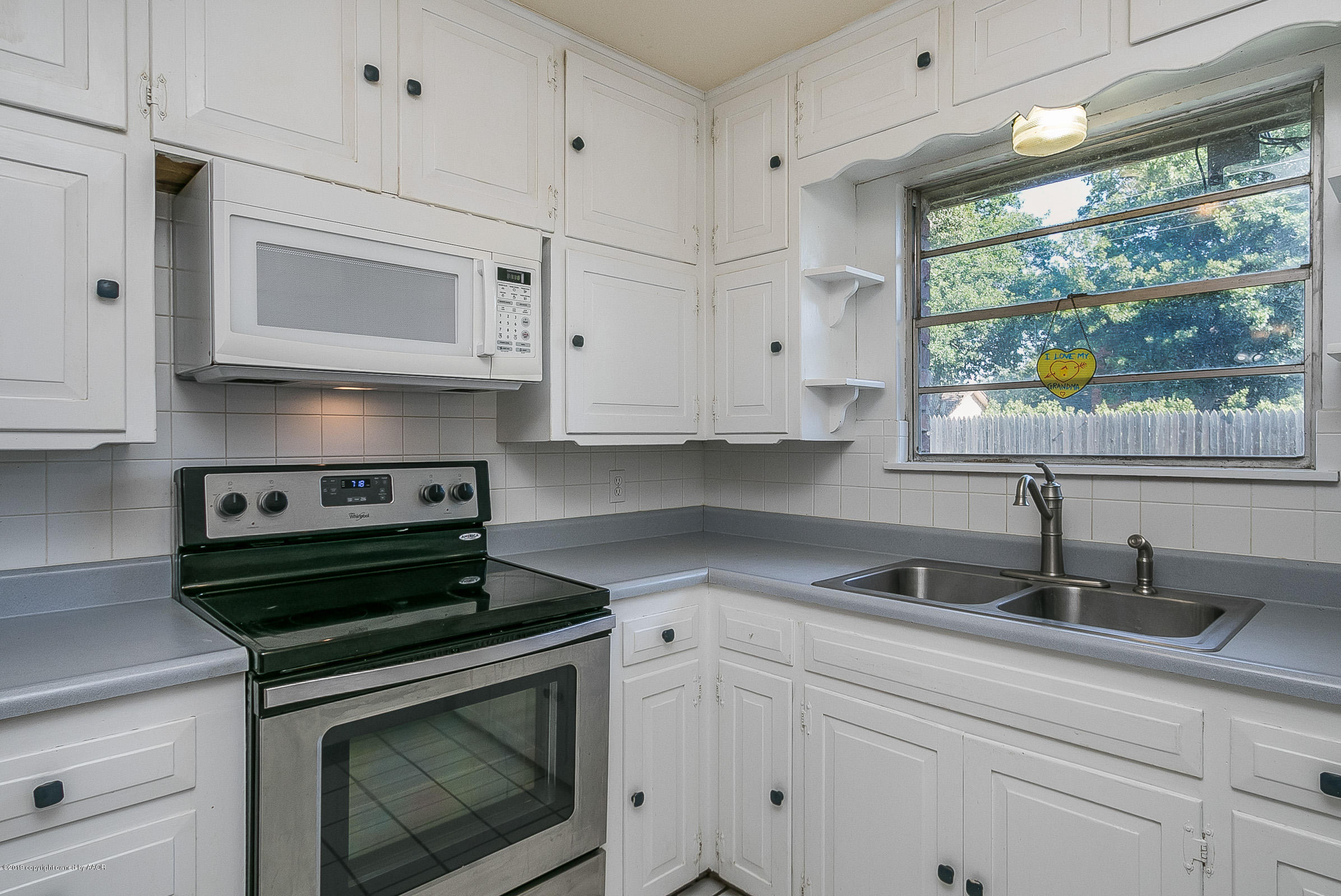 6016 Elmhurst Road Amarillo, TX 79106 - Photo 10 of 21 a kitchen with white cabinets a sink and a stove
