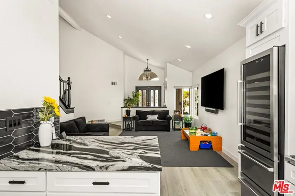 a kitchen with stainless steel appliances kitchen island granite countertop a refrigerator a stove top oven a sink dishwasher and white cabinets with wooden floor