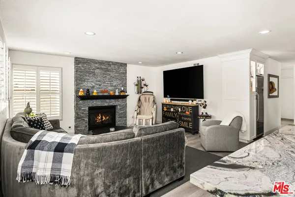 a kitchen with stainless steel appliances kitchen island granite countertop a stove top oven a sink dishwasher a dining table and chairs with wooden floor