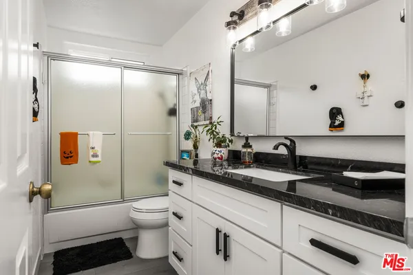 a bathroom with a granite countertop toilet sink and mirror