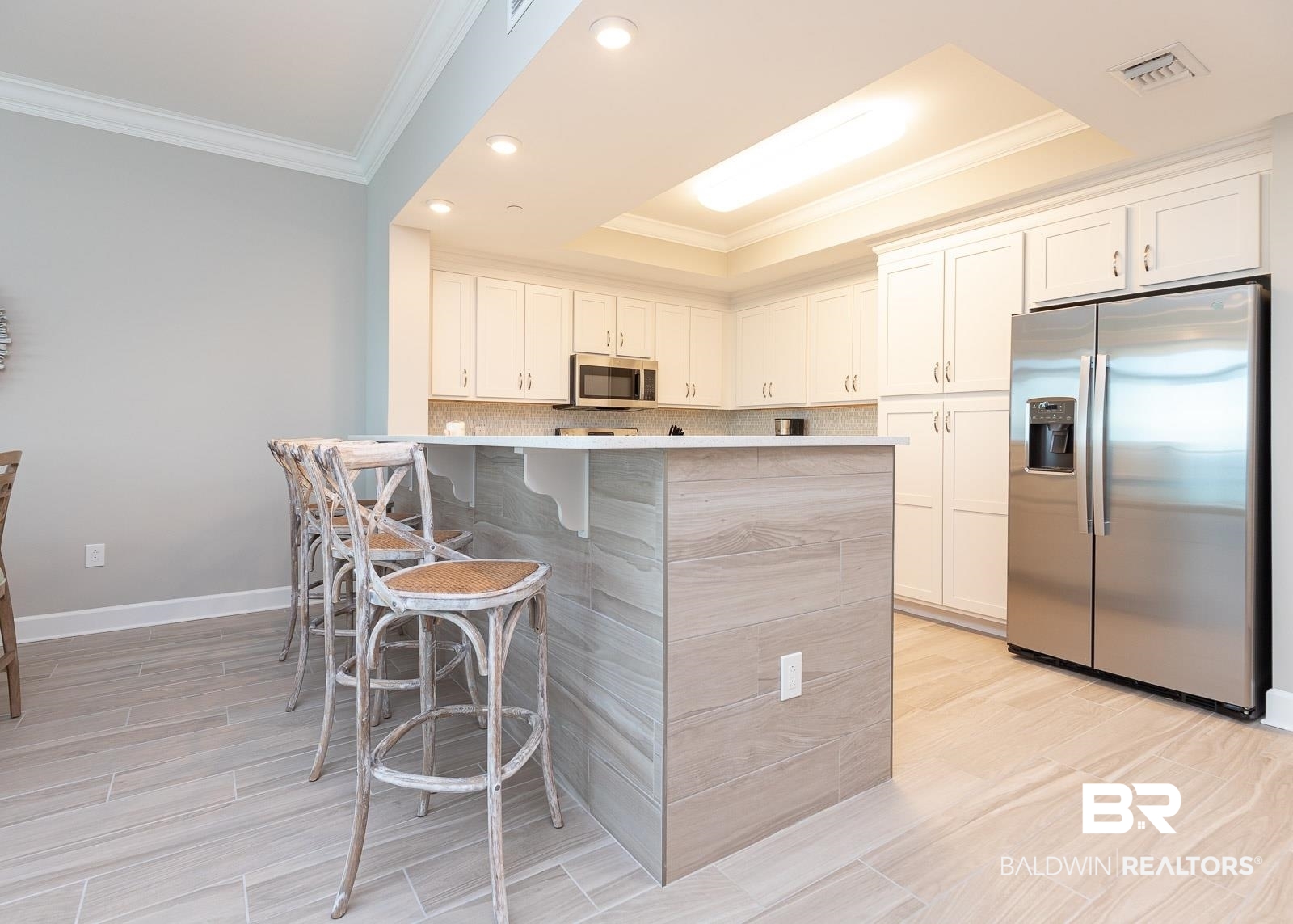 23008 Perdido Beach Boulevard, Unit 2003 Orange Beach, AL 36561 - Photo 6 of 35 Kitchen with appliances with stainless steel finishes, a kitchen breakfast bar, white cabinets, and a raised ceiling