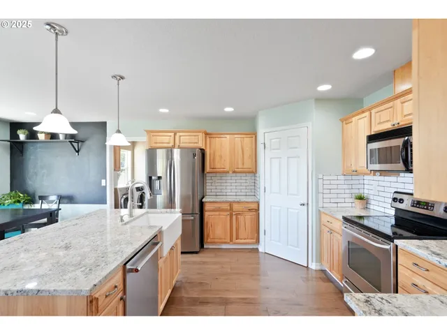 a kitchen with stainless steel appliances kitchen island granite countertop a sink stove and refrigerator
