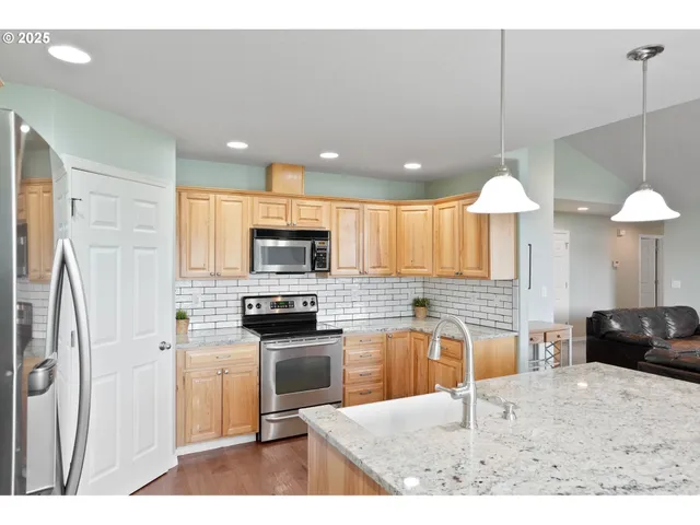 a kitchen with stainless steel appliances kitchen island granite countertop a stove top oven a sink a counter top space and cabinets