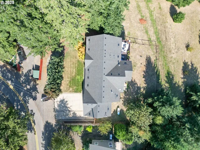 an aerial view of a house with outdoor space and trees all around