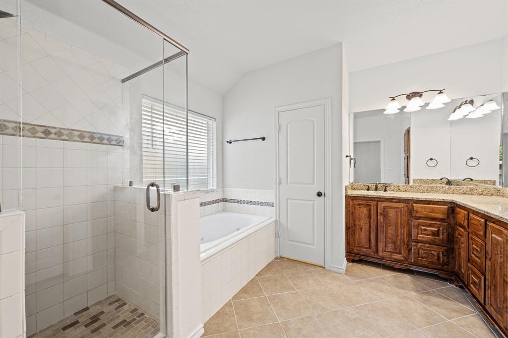 229 Firefly Drive Springtown, TX 76082 - Photo 12 of 33 Bathroom featuring a glass-enclosed shower with tile surround, a built-in jetted tub, a window with blinds, a double vanity with stone countertops and wood cabinetry, and tile flooring