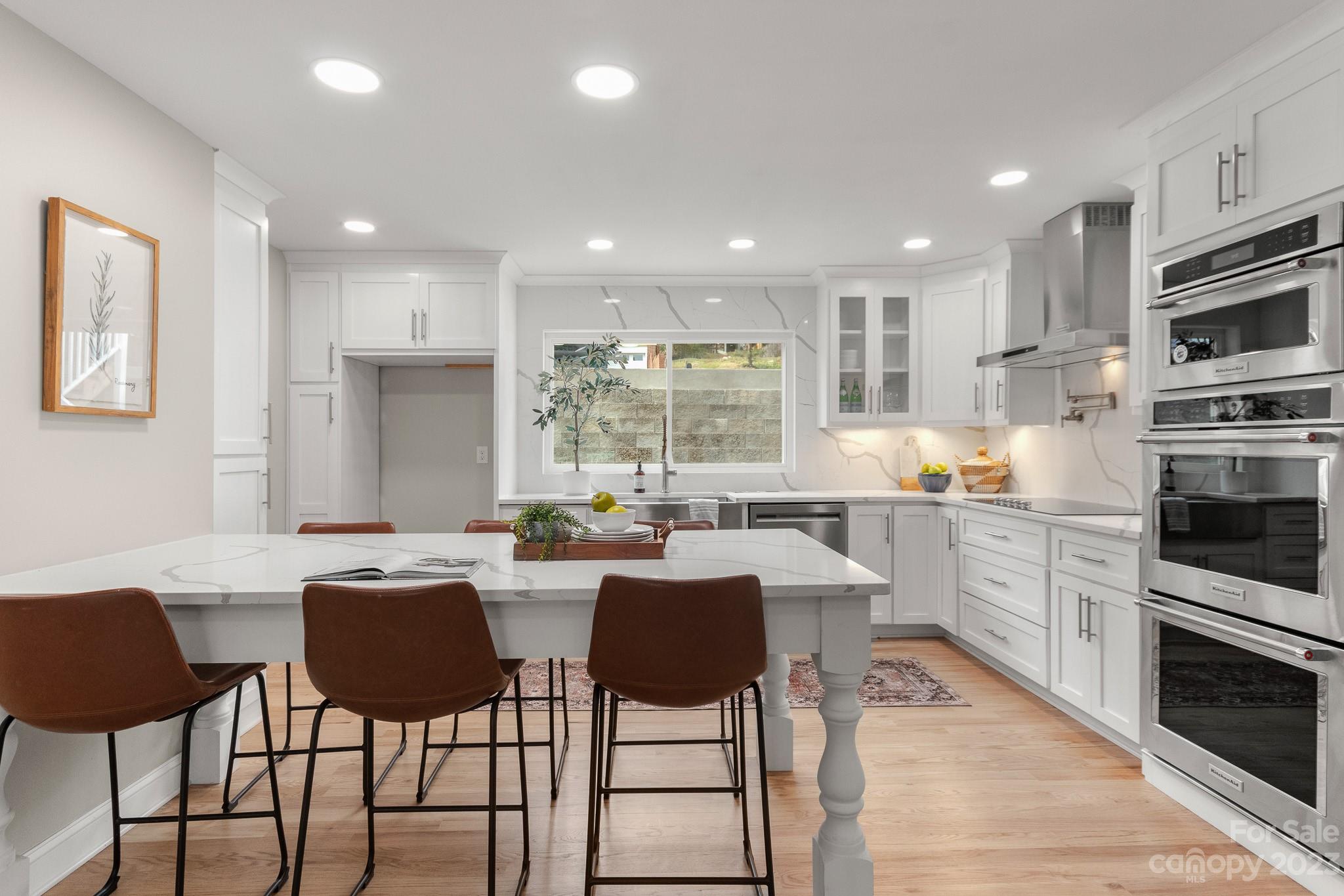 a kitchen with stainless steel appliances kitchen island granite countertop a stove a sink a dining table and chairs