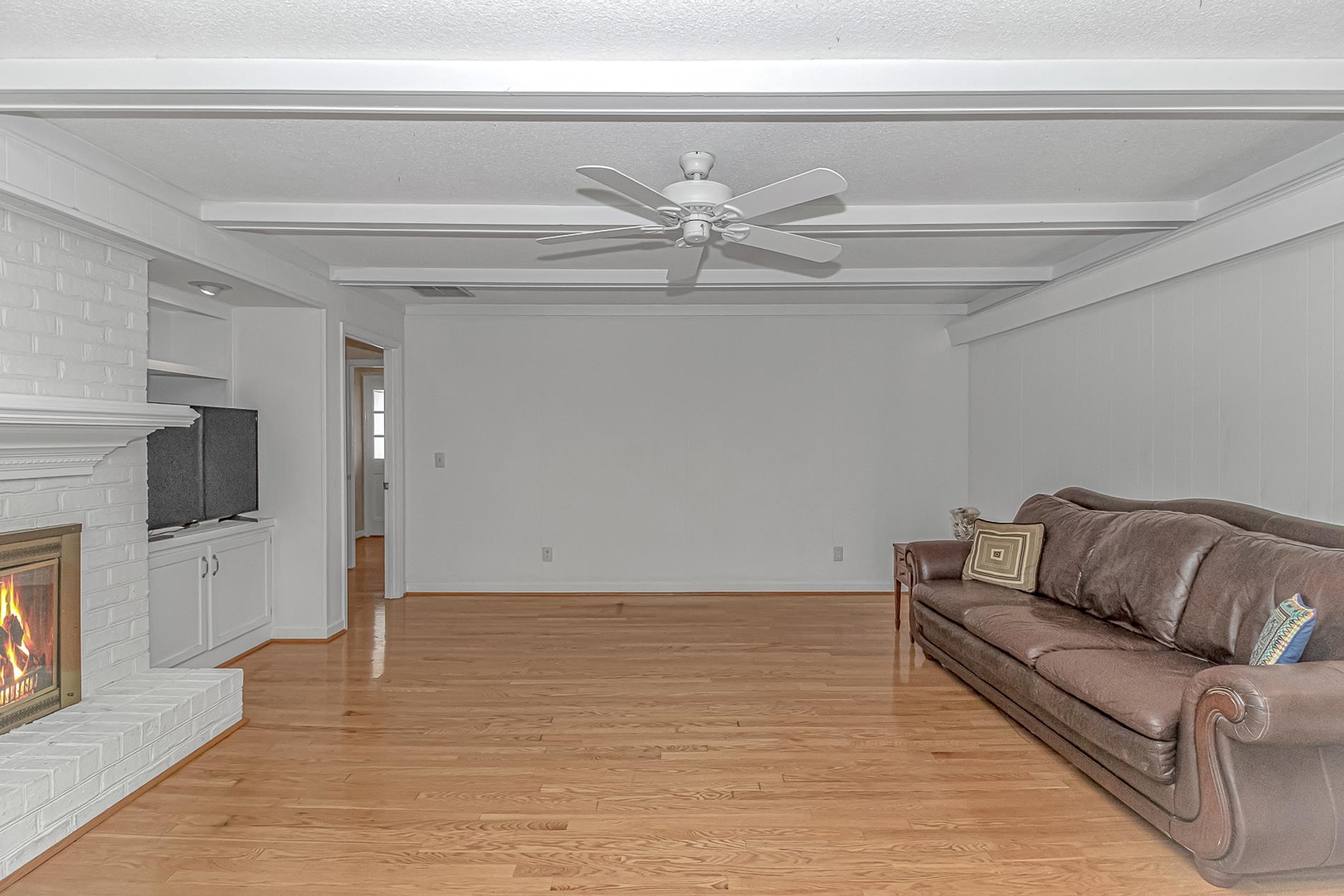 119 University Circle Conway, SC 29526 - Photo 12 of 40 Living room with beamed ceiling, a brick fireplace, a textured ceiling, light wood-style flooring, and ceiling fan