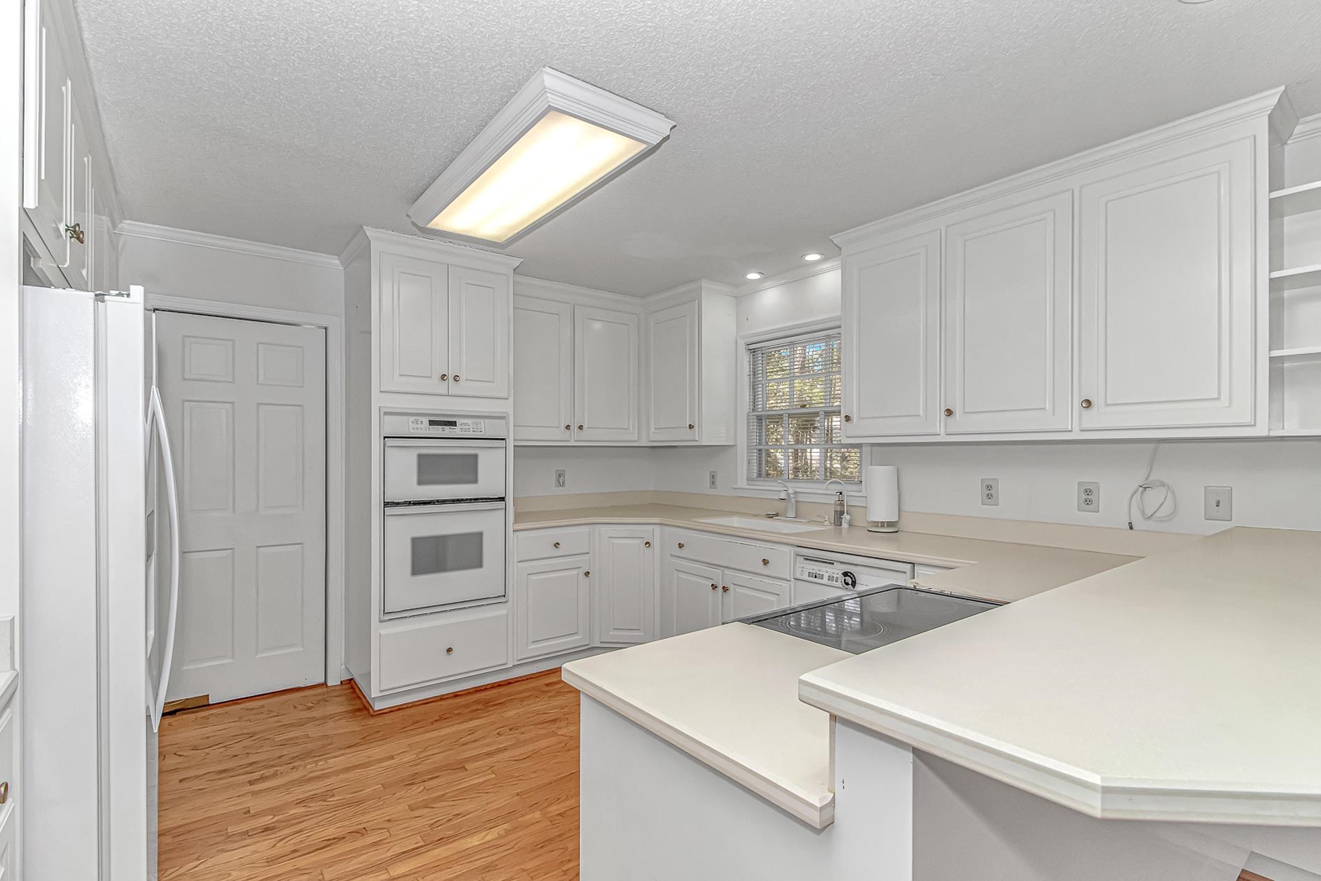 119 University Circle Conway, SC 29526 - Photo 9 of 40 Kitchen featuring open shelves, white appliances, white cabinetry, crown molding, and a peninsula