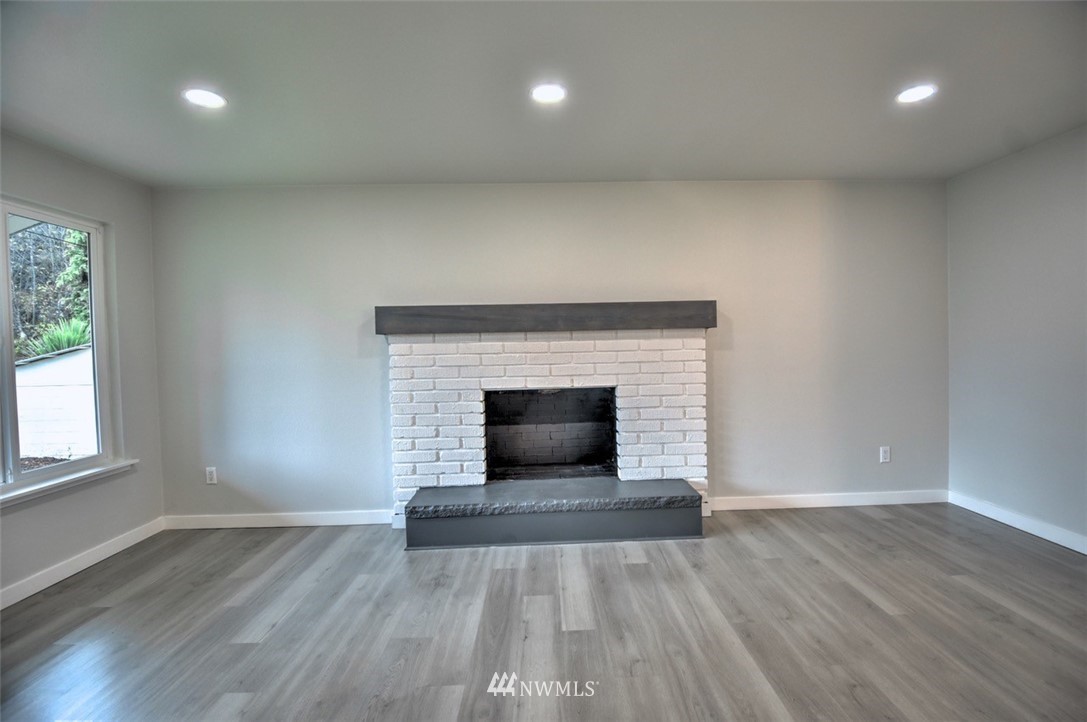 10330 185th Avenue Southwest Rochester, WA 98579 - Photo 7 of 22 an empty room with wooden floor and fireplace