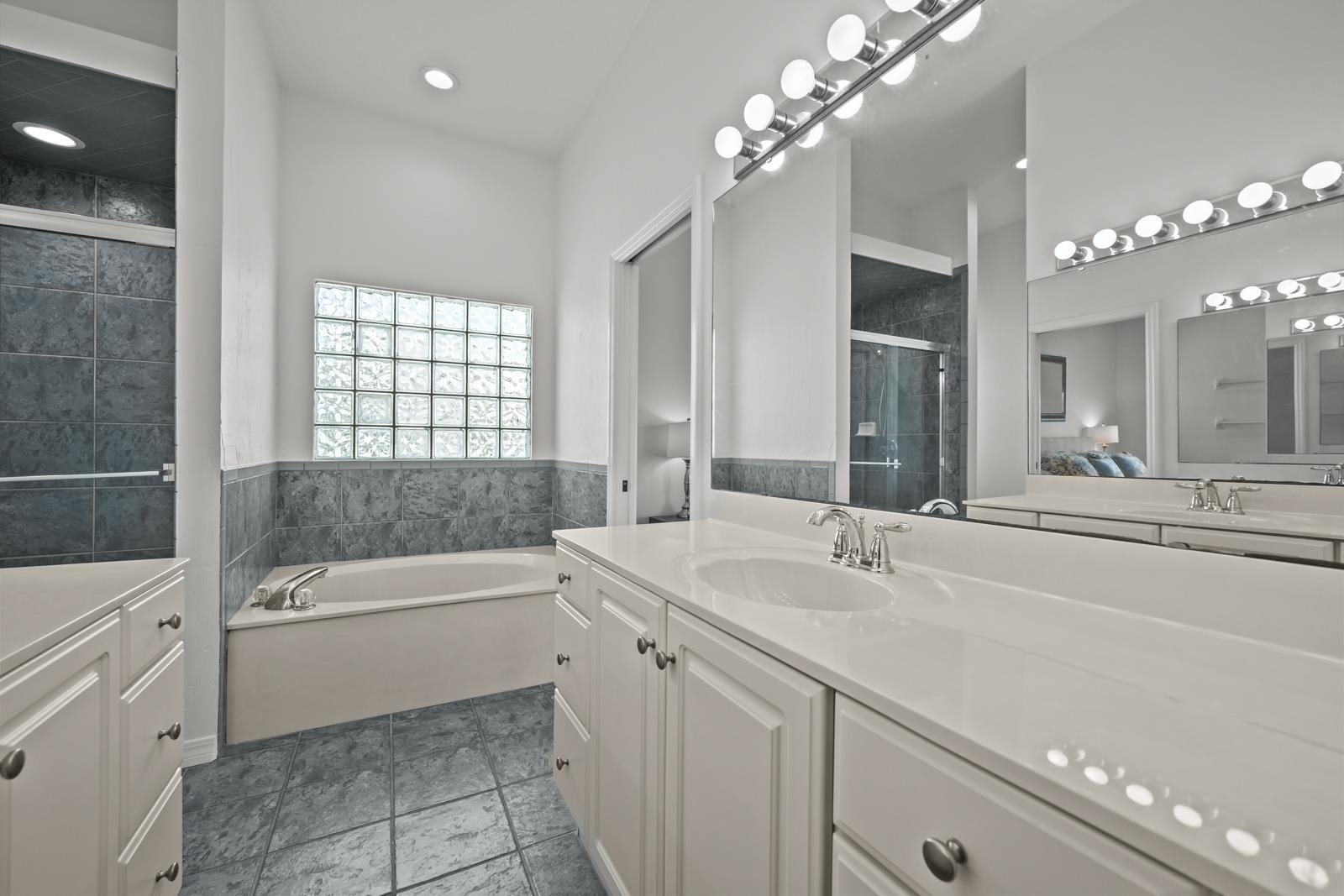 9224 July Lane St. Augustine, FL 32080 - Photo 40 of 88 a bathroom with a sink a large mirror and a bathtub with shower