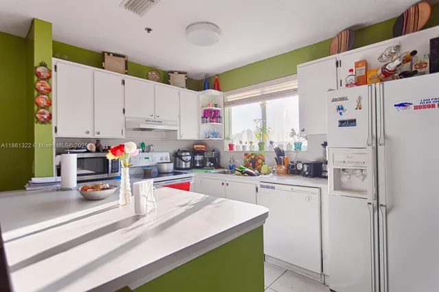 a kitchen with a refrigerator a stove and white cabinets