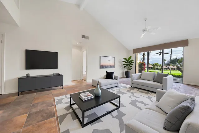 a living room with furniture a flat screen tv and a large window