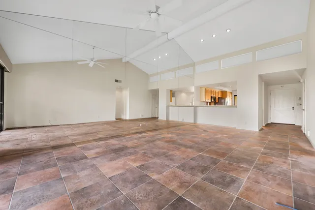 a view of a hallway to an empty room with wooden floor and a window
