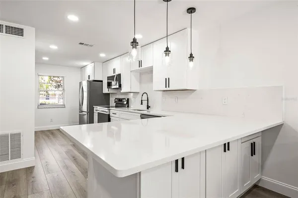 a kitchen with kitchen island a stove a sink a center island and wooden floor