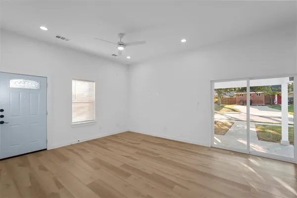 an empty room with wooden floor and windows