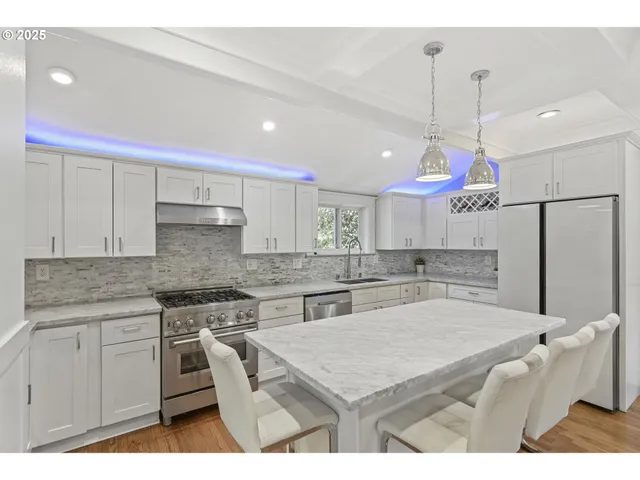 a kitchen with kitchen island a counter top space a sink stainless steel appliances and cabinets