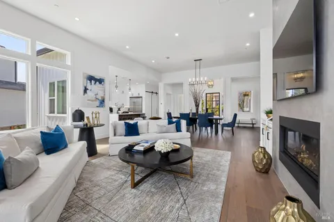 a living room with furniture a fireplace and a dining table with wooden floor