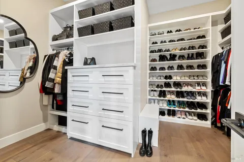 a view of walk in closet with clothes and shoes