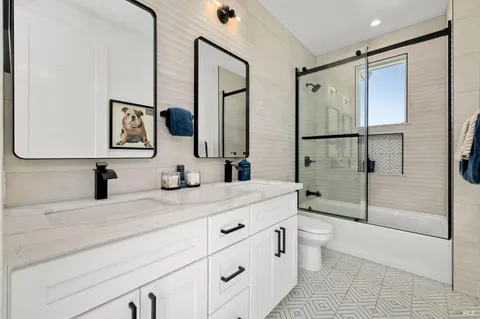 a bathroom with a double vanity sink toilet mirror and shower