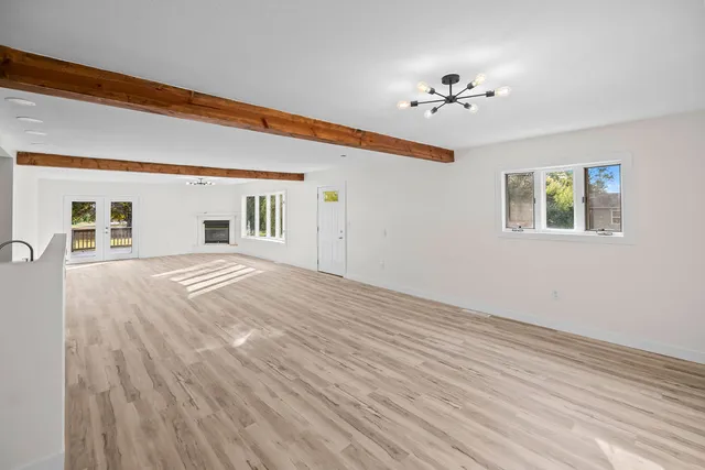 a view of an empty room with wooden floor and a chandelier fan
