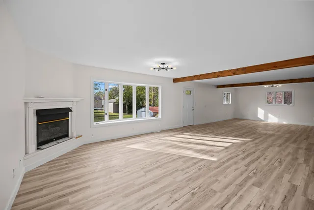 a view of empty room with wooden floor and fireplace