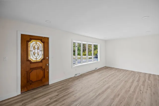 a view of an empty room with a window and wooden floor