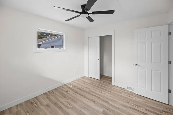 an empty room with wooden floor ceiling fan and windows