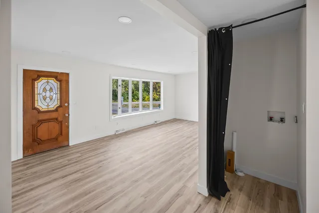 a view of an empty room with window and wooden floor