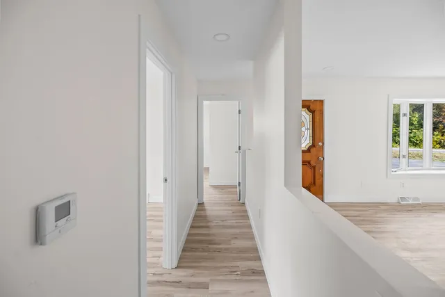 a view of a hallway with wooden floor and a window