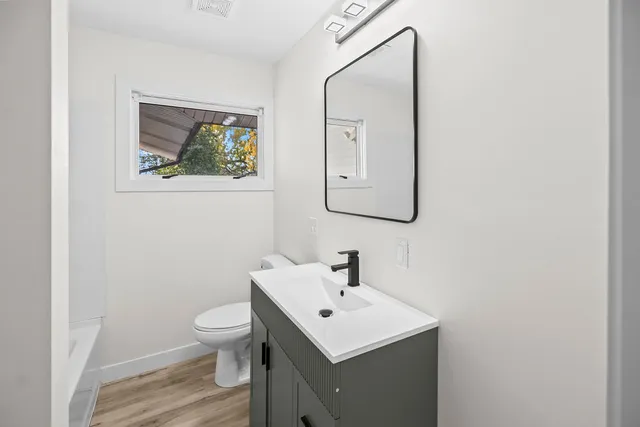 a bathroom with a toilet a sink and mirror