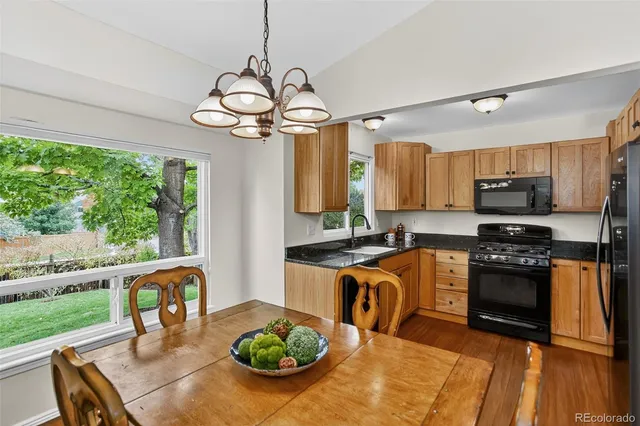 a kitchen with stainless steel appliances granite countertop a stove top oven a sink a stove dining table and chairs with wooden floor