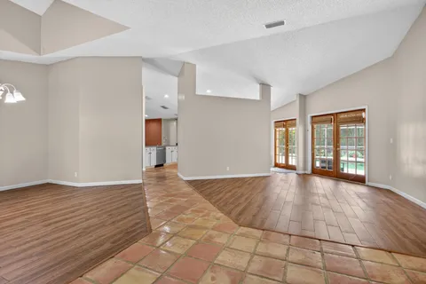 a view of an empty room with window and wooden floor