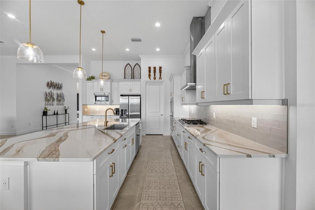 5975 Blakeney Loop Apollo Beach, FL 33572 - Photo 20 of 100 a large white kitchen with stainless steel appliances granite countertop a sink a stove and a refrigerator