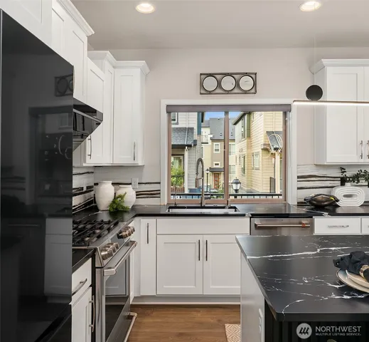 a kitchen with stainless steel appliances granite countertop a stove a refrigerator a sink a stove and white cabinets