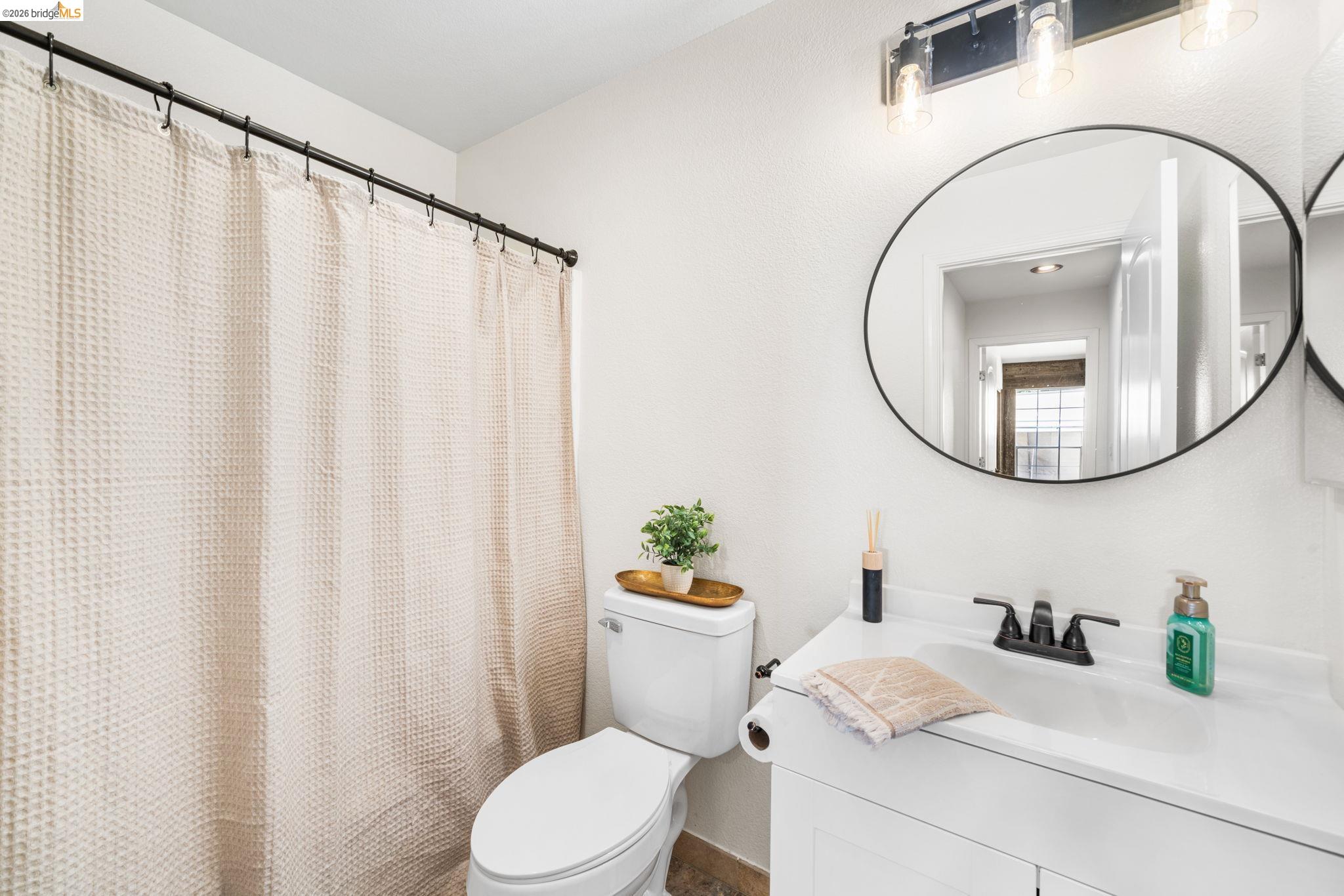 1186 El Rio Court Livermore, CA 94551 - Photo 24 of 60 Bathroom featuring a white vanity with integrated sink, black-finish faucet, and a round black-framed mirror