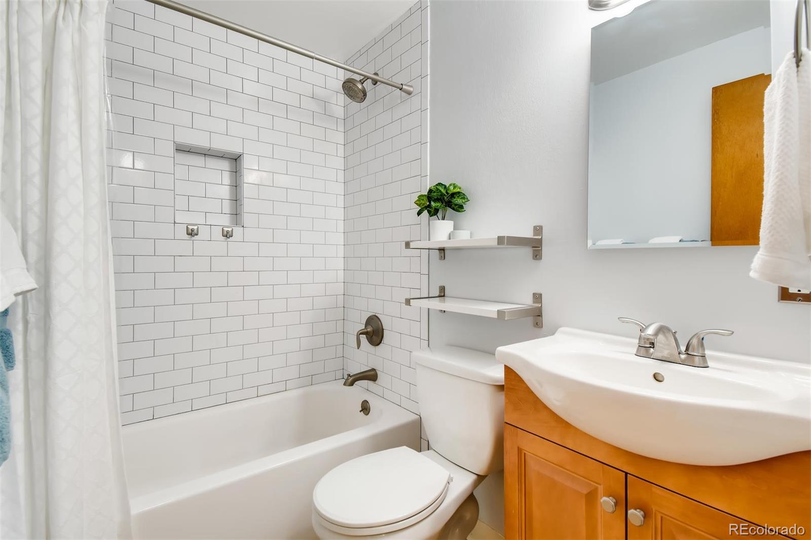 1377 South Oneida Street Denver, CO 80224 - Photo 15 of 27 a bathroom with a sink a toilet a mirror a shower and bathtub