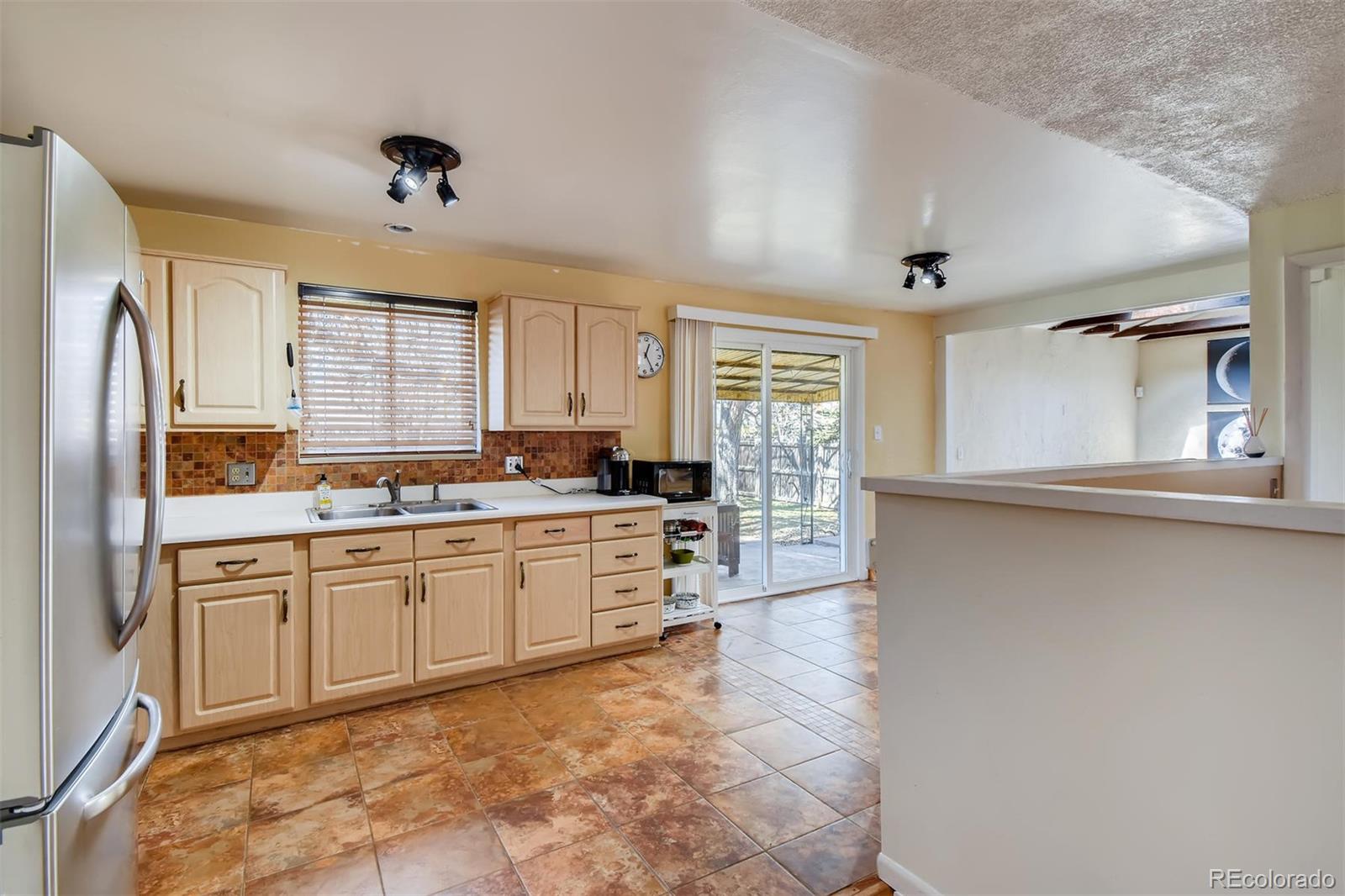 1377 South Oneida Street Denver, CO 80224 - Photo 8 of 27 a large kitchen with kitchen island a stove a sink dishwasher and a refrigerator with wooden floor