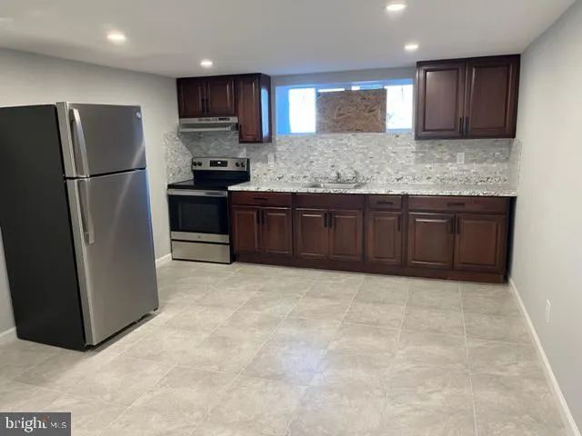 a kitchen with granite countertop a refrigerator and a sink